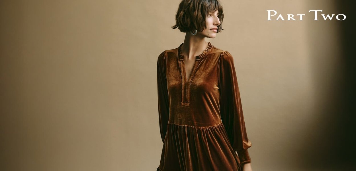 Braunes Samtkleid mit langen Ärmeln, einem gerafften Ausschnitt und einem plissierten Rock. Vor neutralem Hintergrund. Elegante Designdetails sichtbar.