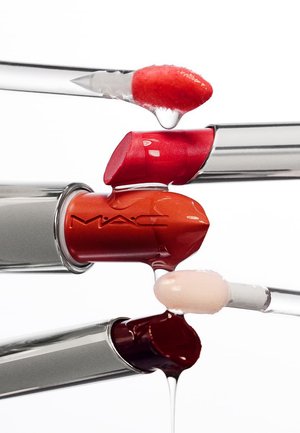 Tre MAC-læbestifter i røde, orange og mørkerøde nuancer med matchende lipgloss-applikatorer, der drypper flydende gloss.
