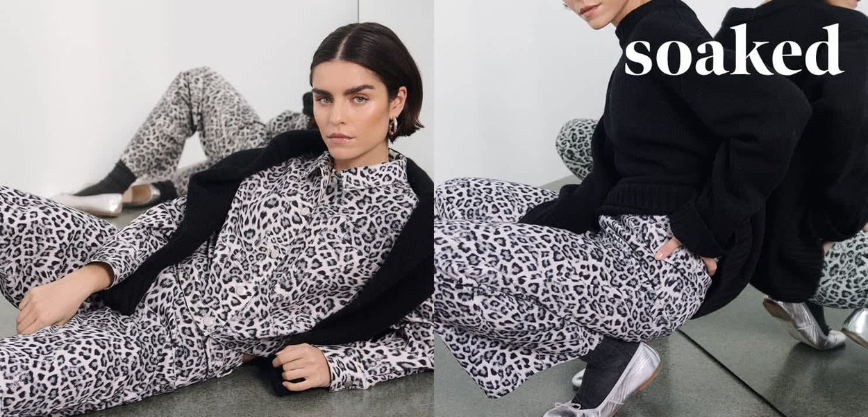 Kleidung mit Leopardenmuster in Grautönen und Schwarz, kombiniert mit einer strukturierten schwarzen Strickjacke und silbernen Slip-On-Schuhen. Reflektierende Oberfläche darunter.