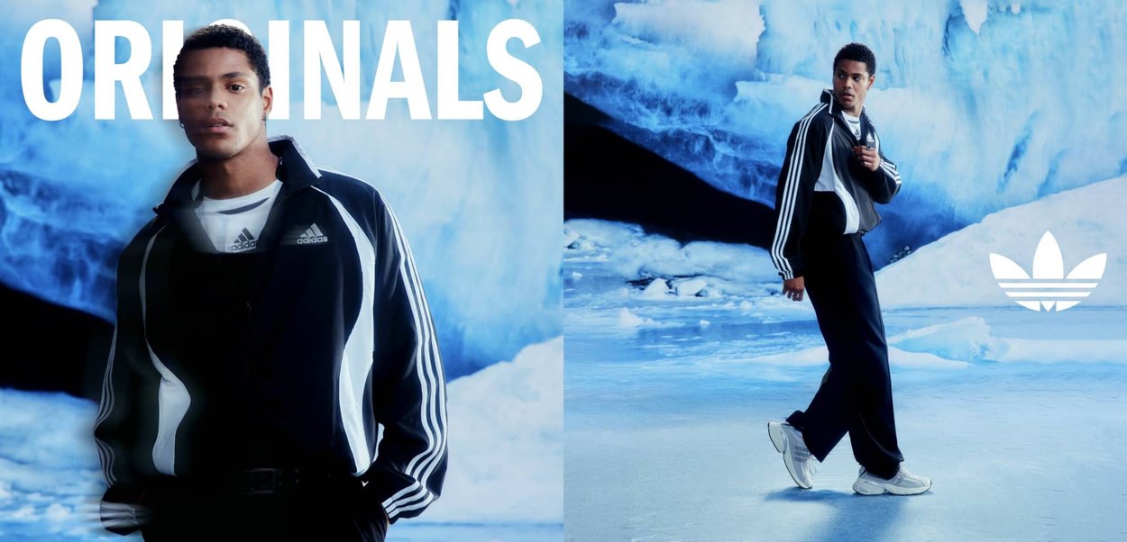 Junger Mann im schwarz-weißen Adidas-Trainingsanzug, der in einer eisblauen Höhle posiert und geht, mit sichtbarem Schriftzug "ORIGINALS" und Adidas-Logo.