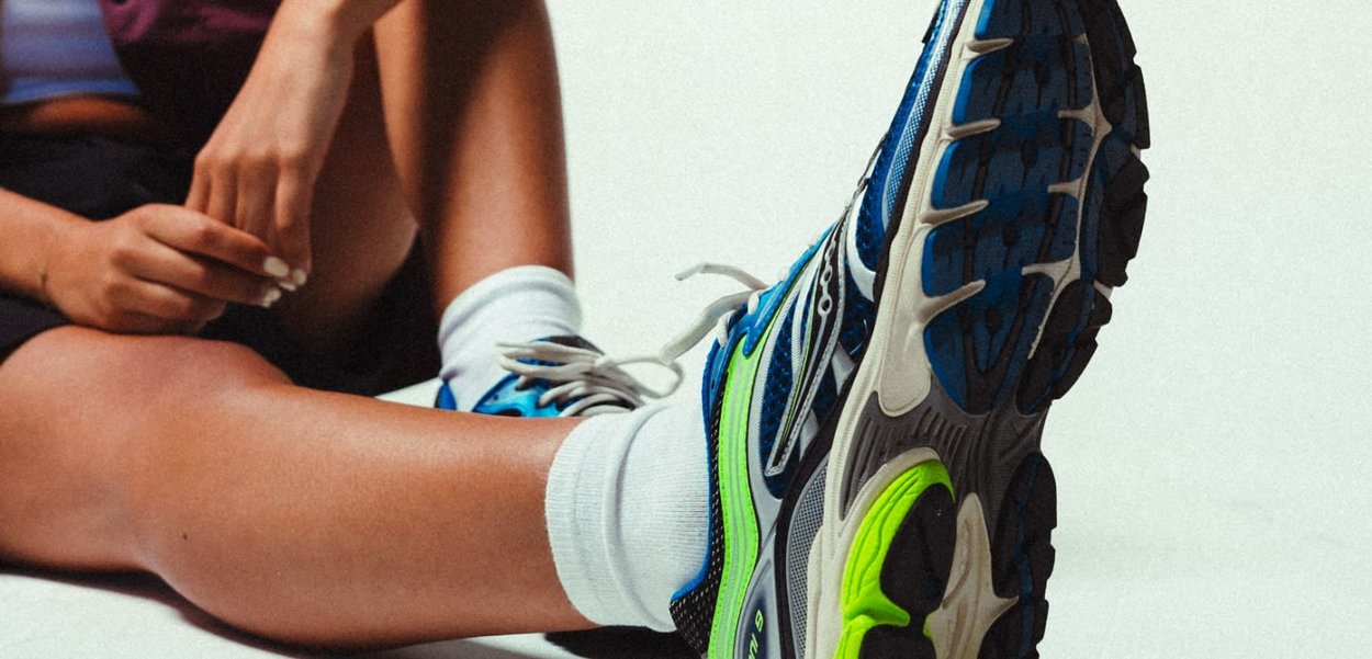 Scarpe sportive con una tomaia in mesh blu e nera, dettagli verdi e una suola testurizzata progettata per aderenza e ammortizzazione.