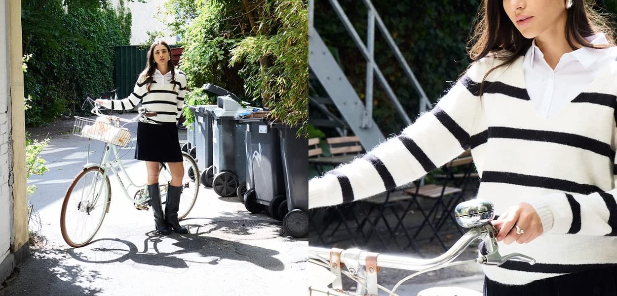 Hellblaues Fahrrad mit einem Drahtkorb, kombiniert mit einem schwarzen Rock und einem weißen Pullover mit schwarzen horizontalen Streifen. Die Szenerie befindet sich im Freien.