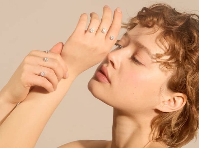 �Ασημένιες δαχτυλίδια με κυκλικούς και τετράγωνους σχεδιασμούς, διακοσμημένα με συστάδες μικρών πολύτιμων λίθων, που φοριούνται στα δάχτυλα, με ουδέτερο φόντο.