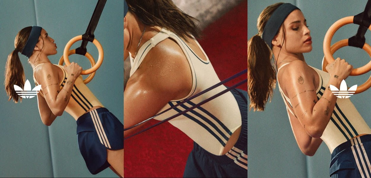 Kobieta z kucykiem i opaską na głowie wykonuje podciągnięcia na gimnastycznych kółkach, ubrana w sportowy strój Adidas z wilgocią na skórze.
