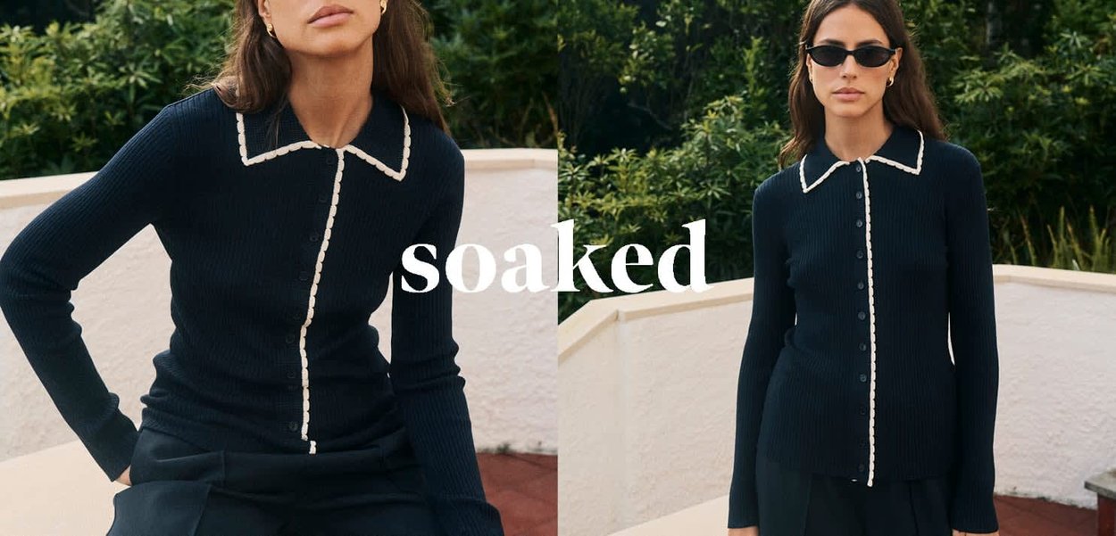 Marineblauer, gerippter Strickcardigan mit weißem Paspelkragen und Knopfverschluss; figurbetonte Silhouette; glatte Textur; getragen zu einem dunklen Outfit.