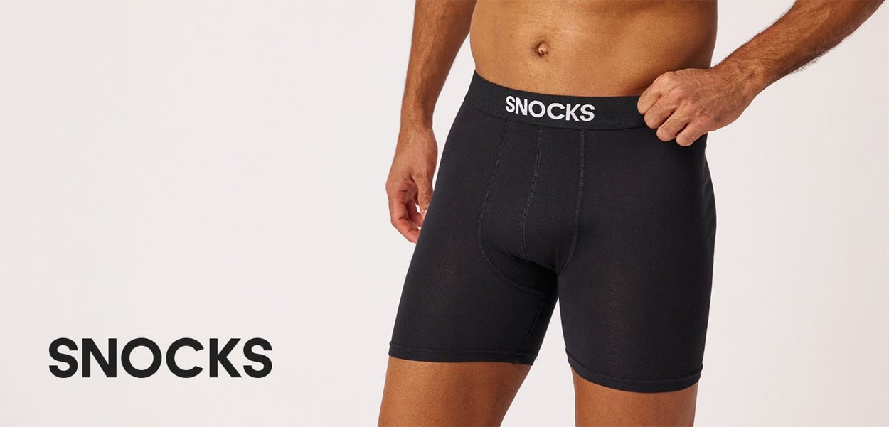 Mand iført sorte Snocks-brandede boxershorts med Snocks-logo synligt på linningen og nederste venstre side.