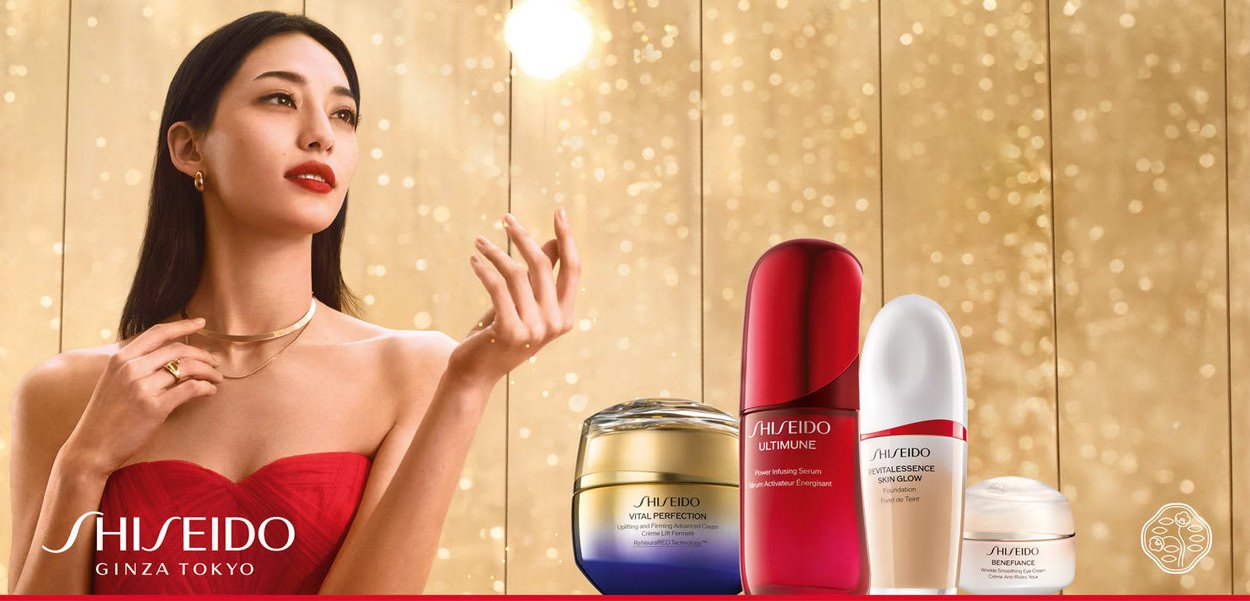 Shiseido Hautpflegeprodukte auf goldenem Hintergrund: blauer Glasbehälter, rotes Serumfläschchen, weißer Foundation-Flakon und Cremetiegel, alle mit schlankem Design.