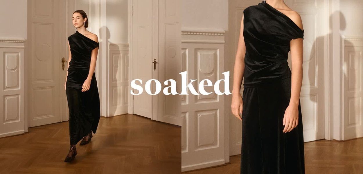 Schwarzes Samtkleid mit einem Schulterstück, drapiertem Design und bodenlangem Rock. Glatte Textur, dezenter Glanz und figurbetonte Silhouette.