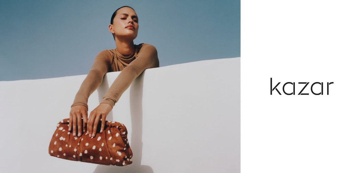 Braune Clutch-Tasche mit Polka-Dots aus einem weichen, strukturierten Stoff, leicht gerafftem Design und rechteckiger Form. Glatte Oberfläche mit dezentem Glanz.