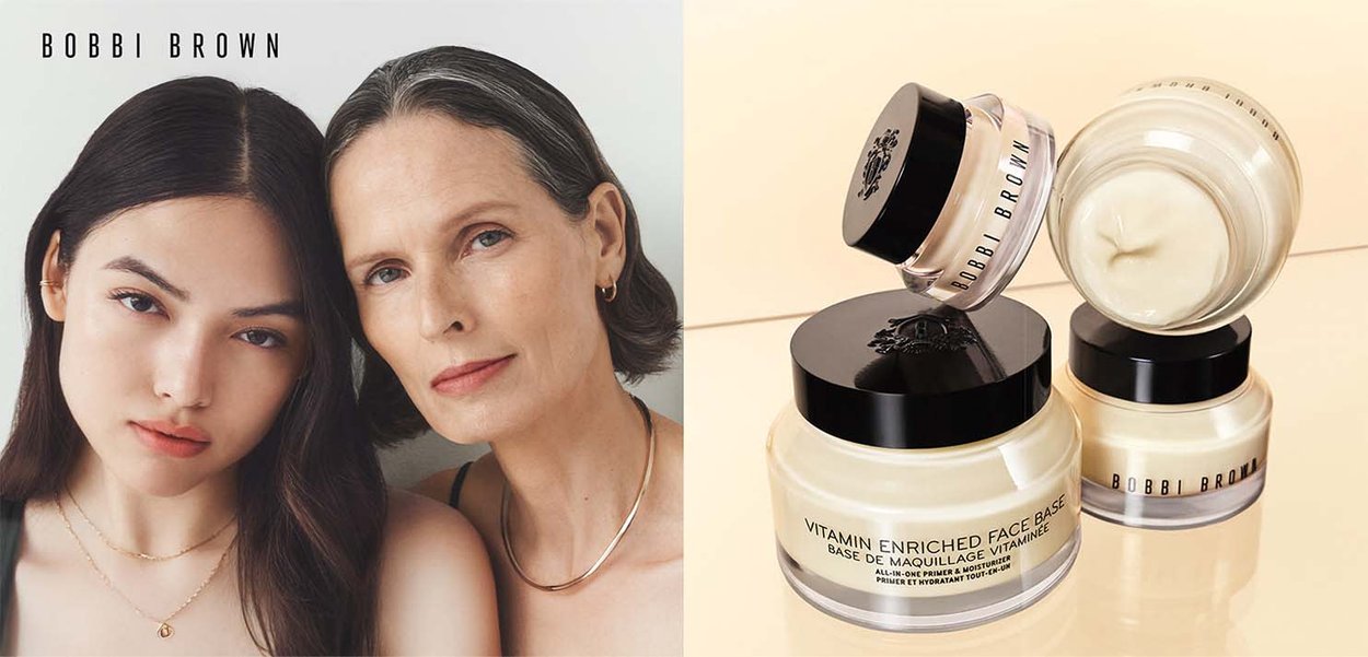 Twee vrouwen met een heldere huid en neutrale gezichtsuitdrukkingen naast drie potten Bobbi Brown Vitamin Enriched Face Base crème op een reflecterend oppervlak.