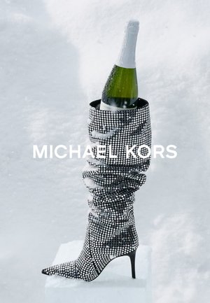 Botek na szpilce wykonany z czarnej tkaniny ozdobionej srebrnymi kryształkami, z marszczonym wzorem, w którym umieszczona jest butelka szampana.