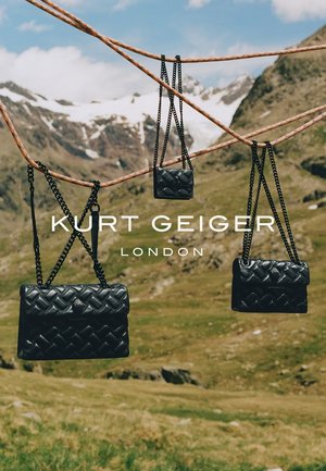 Des sacs à main en similicuir noirs, matelassés, avec des chaînes, suspendus à une corde devant un paysage montagneux. Les modèles varient en taille et en forme.