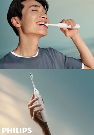 Jongere die tanden poetst met een witte Philips elektrische tandenborstel, vastgehouden in de hand tegen een effen achtergrond.