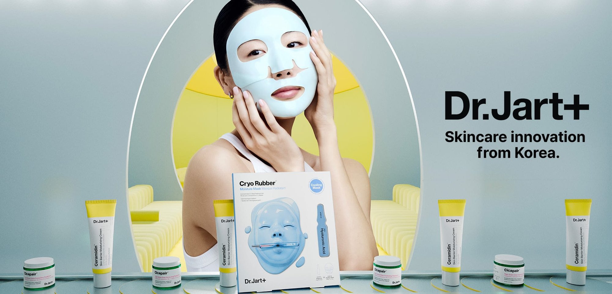 Masque facial Cryo Rubber de Dr. Jart+ en bleu clair, présenté avec des produits de soin de la peau. Les produits comprennent un mélange de tubes et de pots avec des accents blancs et verts.