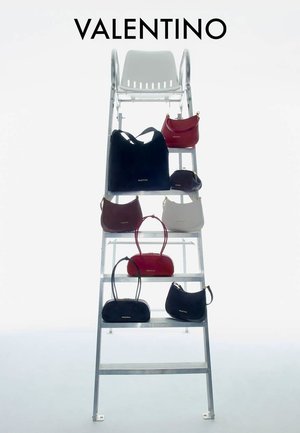 Échelle en métal avec huit sacs à main Valentino en noir, rouge, marron et blanc disposés sur ses marches sur fond blanc.