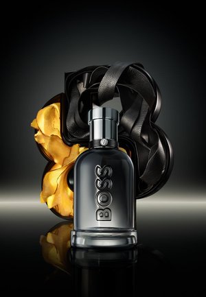 Black and gold bottle of Boss fragrance with a textured black leather wrap, featuring a sleek silver cap and reflective base.