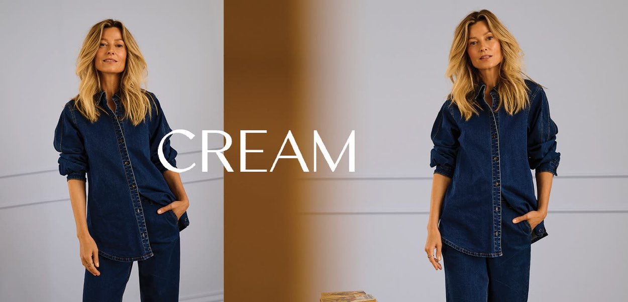 Jeanshemd in tiefem Blau mit durchgehendem Knopfverschluss, hochgekrempelten Ärmeln und lockerer Passform, kombiniert mit passenden Jeanshosen. Text "CREAM" in Weiß.