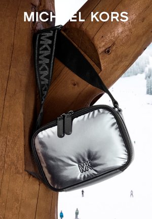 Srebrna metaliczna torebka na ramię z wyściełaną fakturą, wyposażona w czarny pasek z logo i podwójne zamknięcie na zamek. Logo marki wytłoczone z przodu.