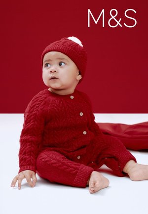 Rode gebreide babyoutfit met een kabelpatroon, bestaande uit een vestje met knopen en een bijpassende muts met een witte pompon. Witte achtergrond.