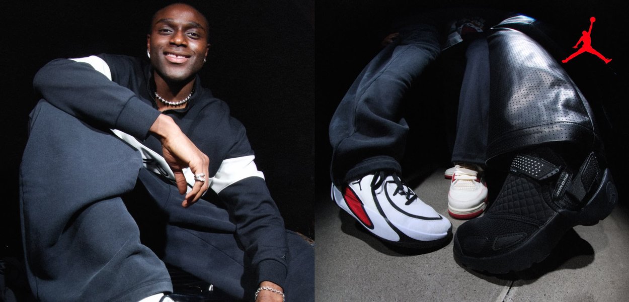 Joven con chándal blanco y negro sonriendo, sentado con una rodilla levantada contra un fondo oscuro con el logo Jumpman rojo.