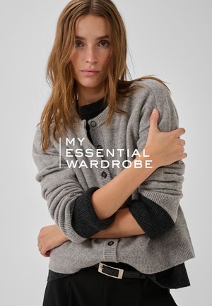 Grau gestrickter Cardigan mit schwarzen Akzenten, Rundhalsausschnitt, Knöpfen und umgeschlagenen Bündchen. Weiche Textur, lockere Passform, kombiniert mit einem schwarzen Gürtel.