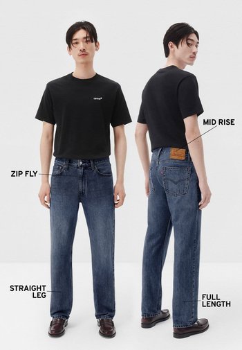 Camiseta negra con logo, jeans azul oscuro de tiro medio y pierna recta, cremallera, largo completo, combinados con calzado oscuro.