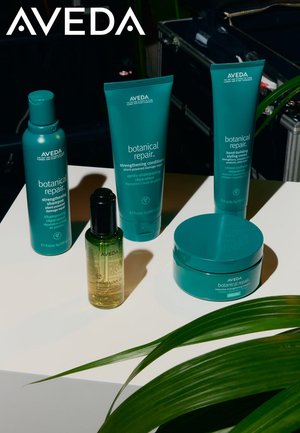 Cinq produits de soin capillaire Aveda en emballage turquoise : shampooing, après-shampooing, crème coiffante, masque intensif et huile, présentés sur une surface blanche.