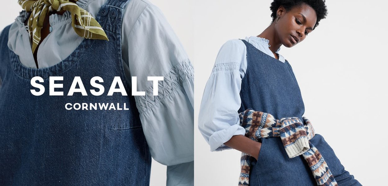 Dunkelblaues Jeans-Latzkleid mit strukturierter Oberfläche, verstellbaren Trägern, großen Taschen und einem passenden gemusterten Strickaccessoire.