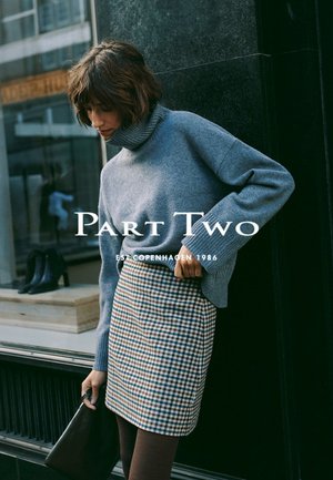Gray knit turtleneck sweater paired with a plaid pencil skirt in shades of brown and cream. Model holding a black handbag.