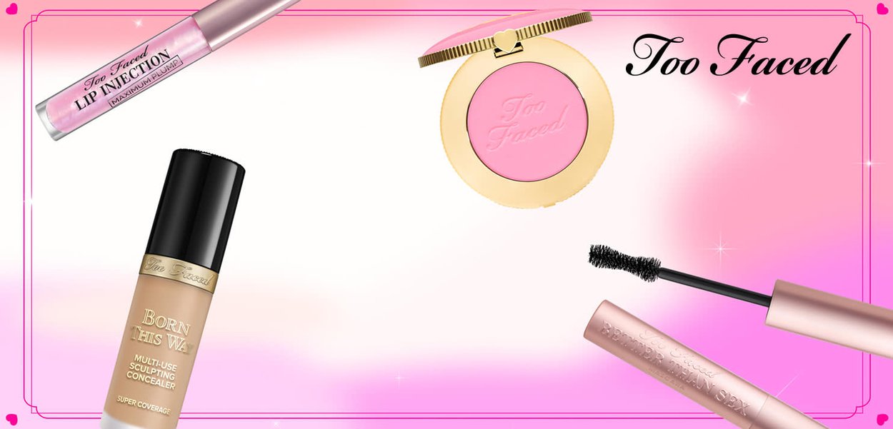 Des produits de maquillage Too Faced comprenant un compact de blush rose, un tube de concealer foncé, un lip plumper transparent et un mascara noir avec une brosse incurvée.