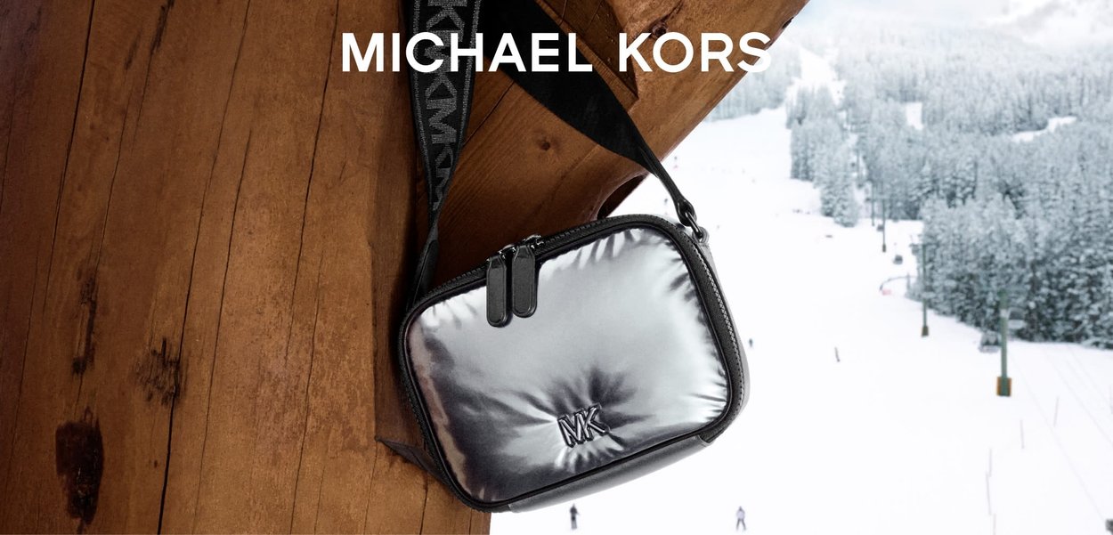 Borsa a tracolla argentata metallizzata con una texture morbida, chiusura a zip, logo in rilievo e tracolla regolabile. Ambientata in un paesaggio innevato.