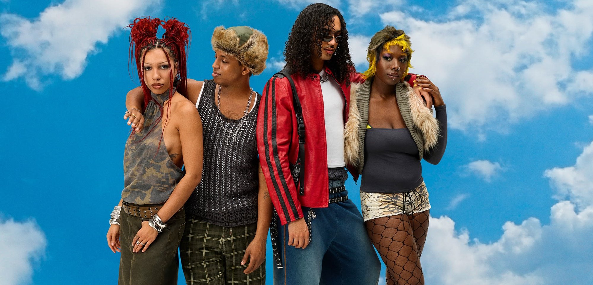 Quatre personnes posent devant un ciel bleu. Les tenues comprennent un haut camouflé, un débardeur tricoté, une veste en cuir rouge, un short à carreaux et des articles avec des accents en fourrure.