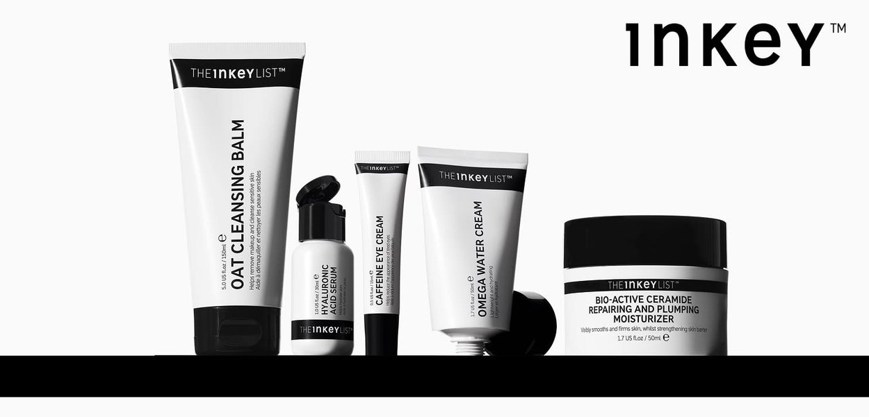 Fem hudplejeprodukter i sort og hvid emballage: rensebalm, serum, øjencreme, vandcreme og fugtighedscreme, vist på række.