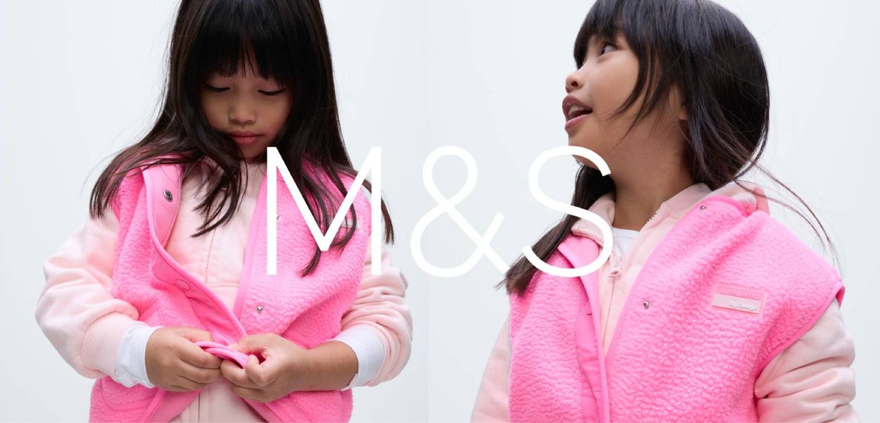 Veste sans manches en polaire rose par-dessus un pull rose clair ; dotée de boutons-pression et d'un logo distinctif. Enfant ajustant la veste, mettant en valeur la texture et la couleur vive.