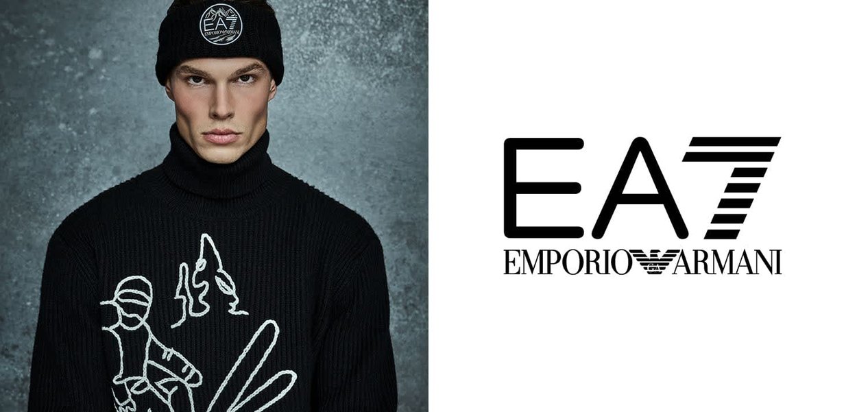 Dolcevita nero lavorato a maglia con design astratto bianco, abbinato a un berretto nero con un logo circolare bianco.