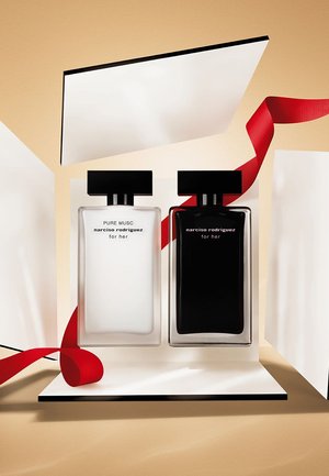 Twee parfumflessen, één van helder glas met het label "Pure Musc" en één van donker glas, tentoongesteld op een wit oppervlak met een rood lint.