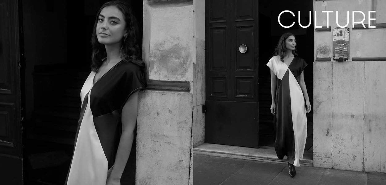 Abito lungo bianco e nero con design asimmetrico in tessuto bianco e nero, caratterizzato da maniche corte e una silhouette fluida e minimalista.