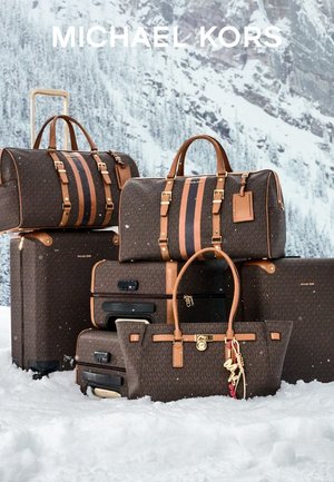 Brunt mønstret bagasjesett med lærdetaljer, inkludert to duffelbags og en tote, satt mot en snødekt bakgrunn.