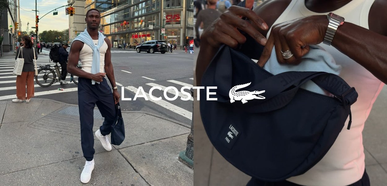 Niebieska torba Lacoste z teksturowanym materiałem, z suwakiem i logo. Model ma na sobie top na ramiączkach, granatowe spodnie i białe sneakersy. Miejska sceneria.