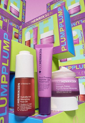 Three skincare products from Ole Henriksen: a red oil bottle, a purple lip treatment tube, and a white moisturizer with a screw-top lid.