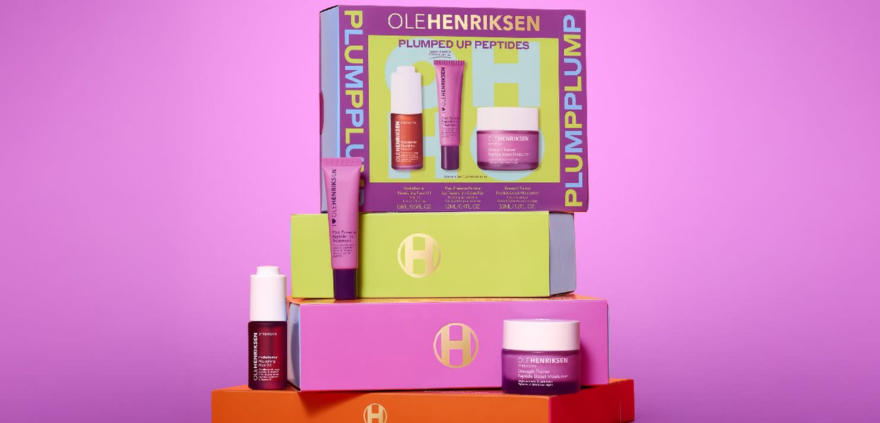 Stacked packaging for skincare products in vibrant colors: pink, purple, orange, and green; includes tubes and jars with labels and branding.