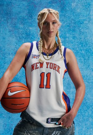 Jugadora de baloncesto con trenzas lleva la camiseta número 11 de Nueva York, sosteniendo un balón de baloncesto sobre un fondo texturizado azul.