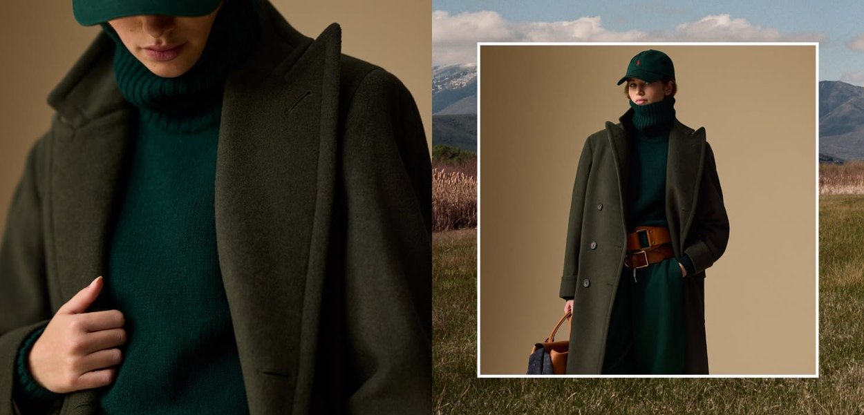 Donna che indossa un maglione a collo alto verde scuro, un cappellino abbinato, un lungo cappotto verde scuro, una cintura larga marrone, mentre tiene una borsa marrone, in piedi contro uno sfondo beige.