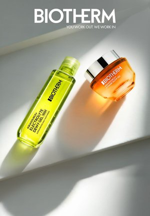 Zwei Biotherm Hautpflegeprodukte auf einer weißen Oberfläche: Flasche mit grünem Elektrolyt-Feuchtigkeitsgel und Dose mit orangefarbenem Vitamin Glow Gel mit silbernem Deckel.