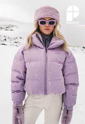 Veste matelassée lavande avec col haut, fermeture éclair et logo. Associée à un chapeau en fourrure assorti, une chemise à motifs et des gants violets.