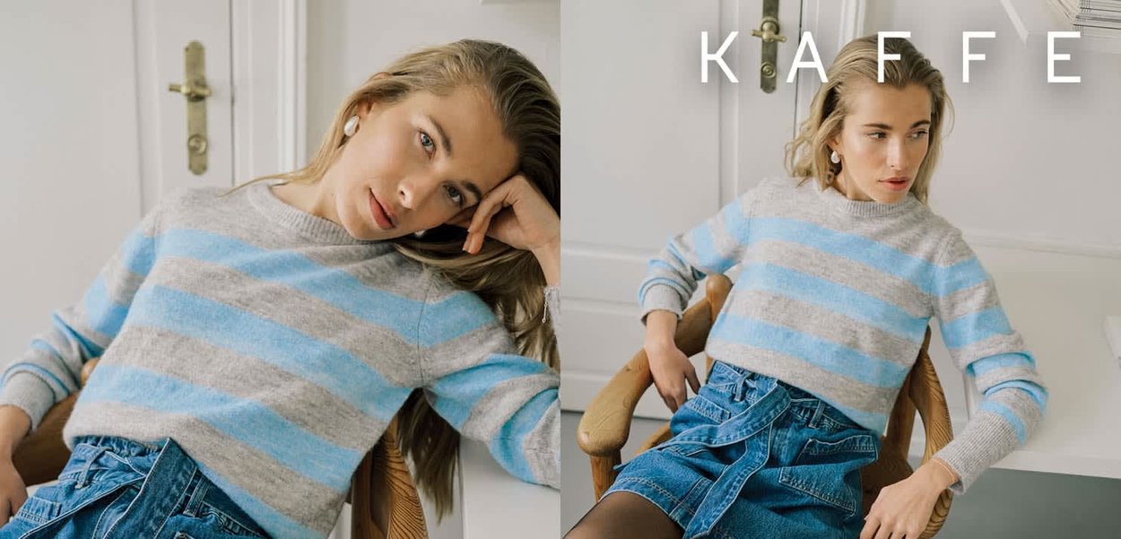 Hellgrauer und blau gestreifter Pullover mit rundem Ausschnitt und gerippten Bündchen, kombiniert mit einem Jeansrock. Innenraum mit neutraler Farbgebung.