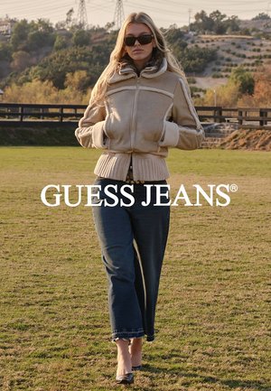 Veste beige zippée avec doublure et poignets en peluche, associée à un jean bleu ample et des talons noirs, le tout sur un fond d'extérieur herbeux.