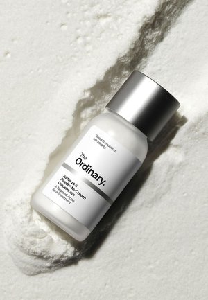 Bottle of The Ordinary Sulfur 10% Powder-to-Cream Concentrate acne spot treatment on a textured white powder background.