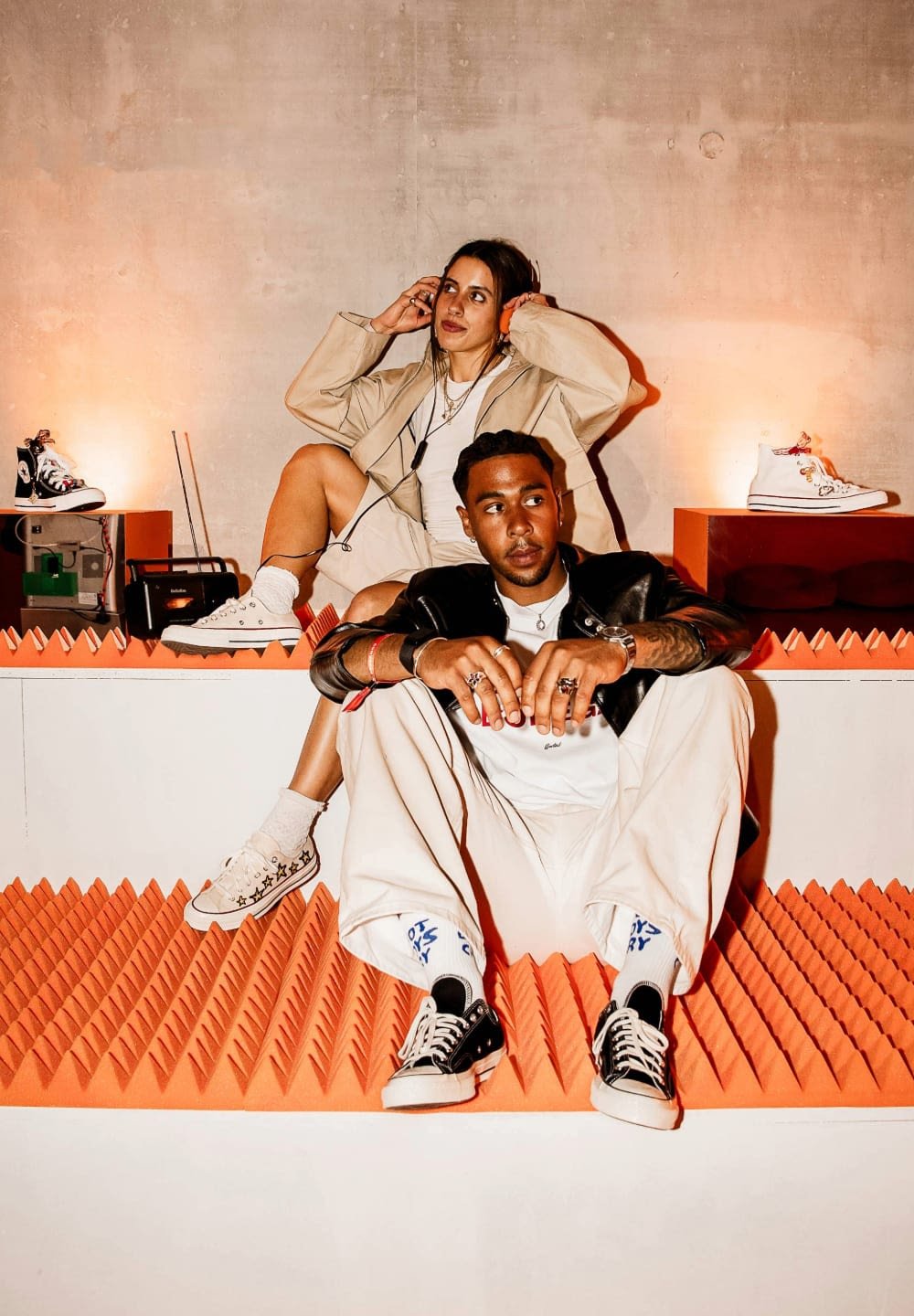 High-top sneakers in black and white; textured platform with orange spikes. Casual outfits: oversized beige jacket, white top, and cream pants.