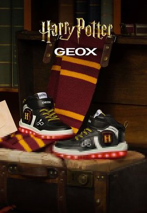 Baskets montantes en noir et blanc avec des semelles rouges lumineuses, présentant des lacets jaunes et des accents inspirés de Harry Potter. Comprend une écharpe rayée.